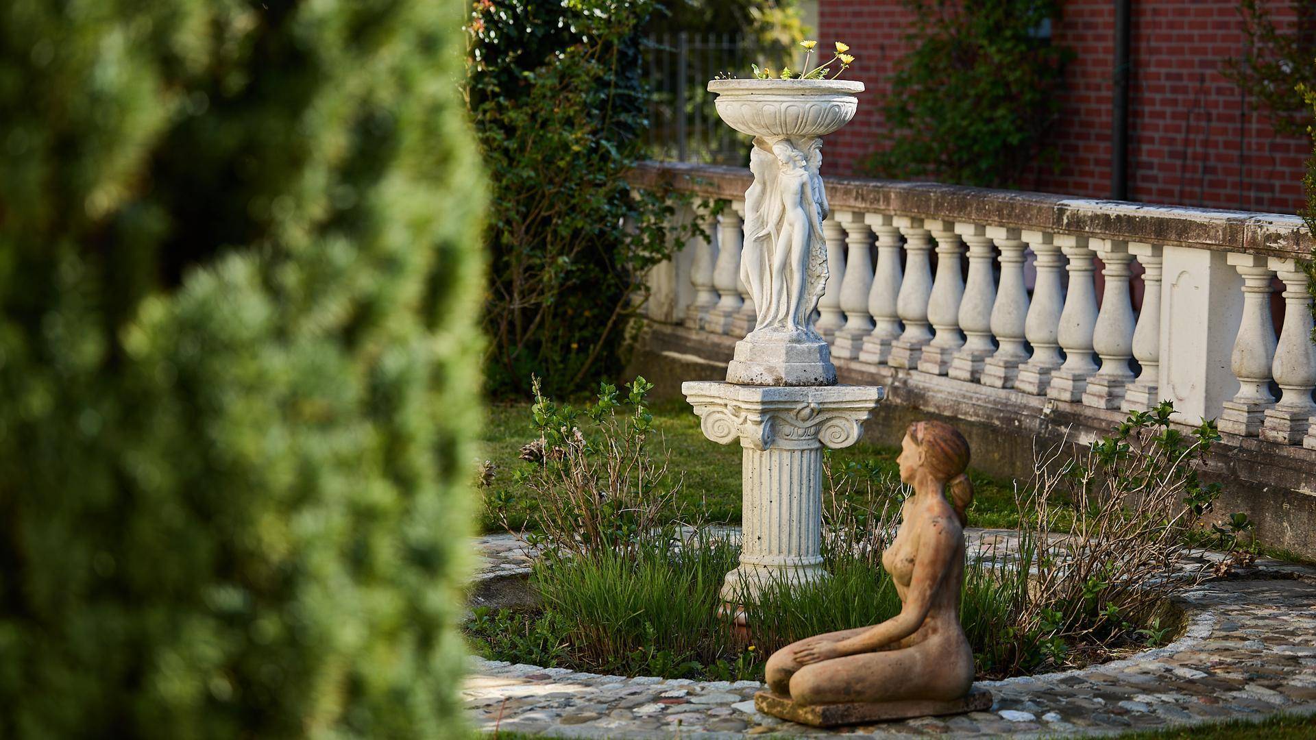 Detailansicht eines Gartens mit klassischer Statue und Balustrade.
