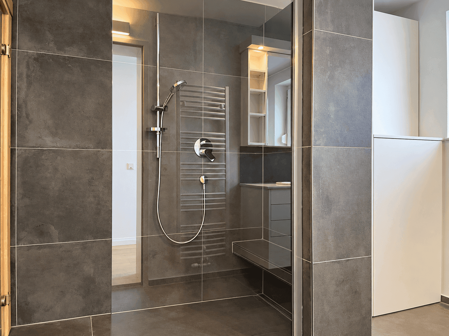 Elegantes Badezimmer mit großer begehbarer Dusche, Glasabtrennung und modernem Design.