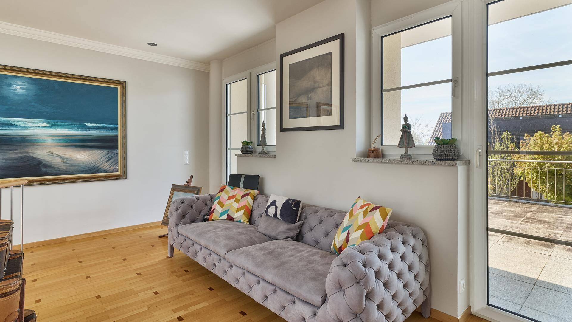 Elegantes Wohnzimmer mit Chesterfield-Sofa, Kunstwerken und Zugang zur Terrasse.