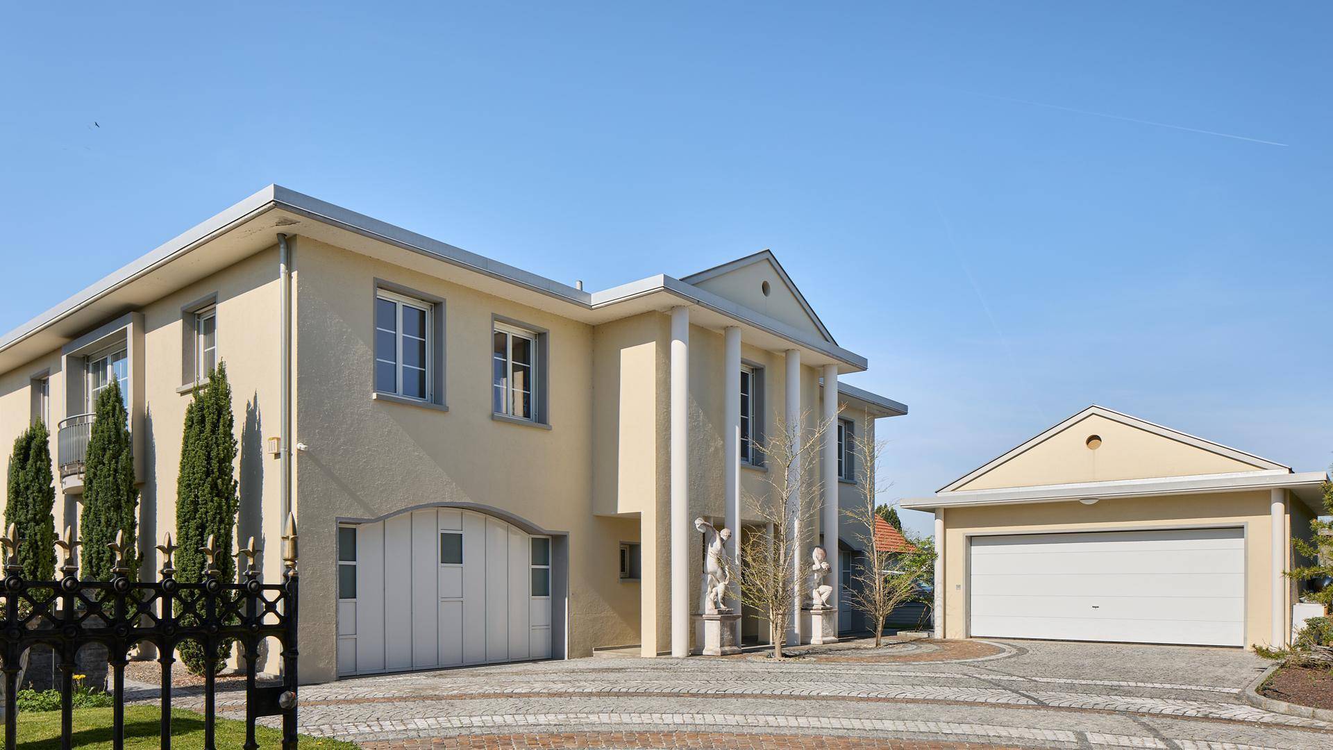 Elegante Villa mit klassischer Architektur, Säulen und separater Doppelgarage.