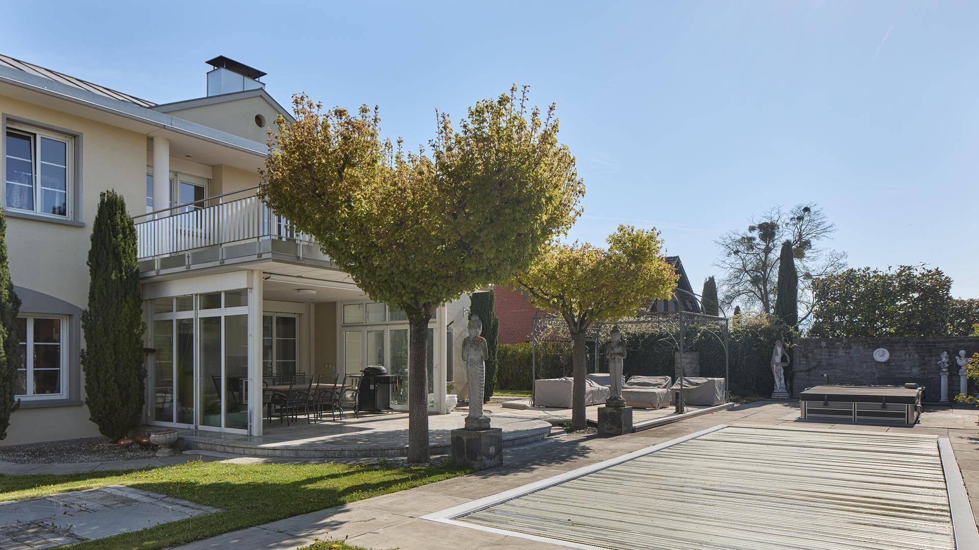 Großer Garten mit Pool, Terrasse und mediterranen Pflanzen und Statuen.