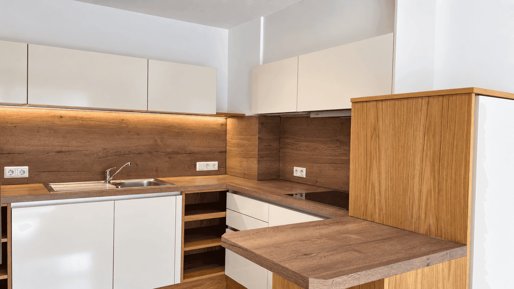 Moderne Einbauküche mit hellen Fronten, Holz-Arbeitsplatten und integrierten Geräten.