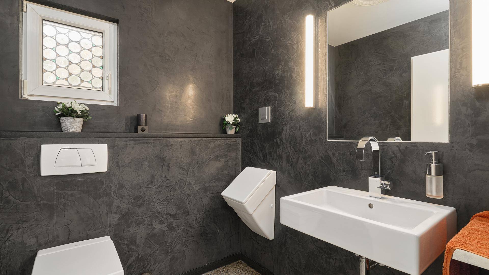 Modernes Gäste-WC mit dunklen Wänden, kleinem Waschbecken und Fenster.