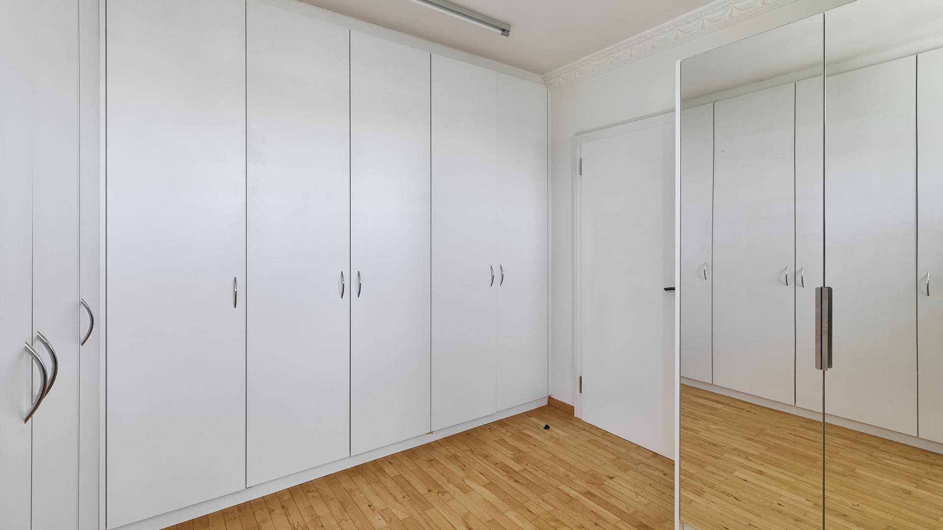 Schlafzimmer mit raumhohen Einbauschränken und hellem Parkettboden.