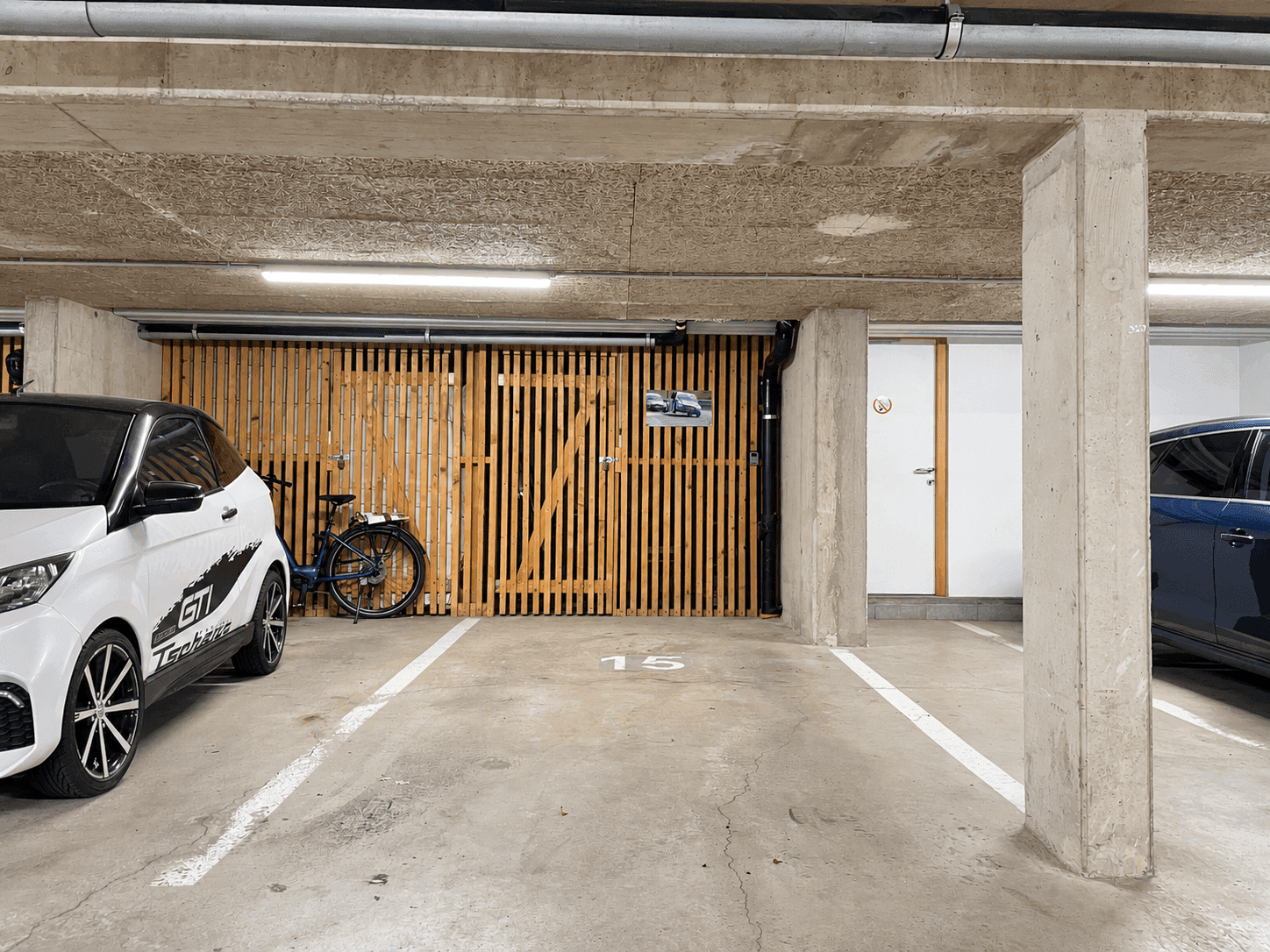 Tiefgarage mit Betonwänden, Beleuchtung und zugewiesenem Stellplatz.