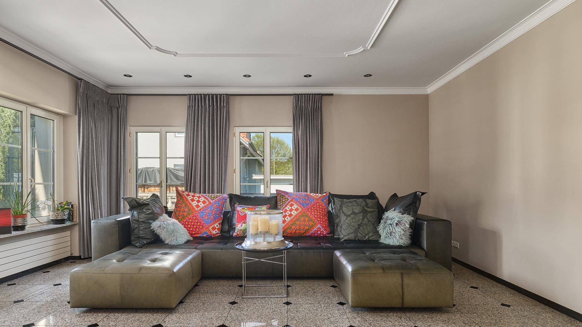 Gemütliches Wohnzimmer mit großem Ecksofa, vielen Kissen und Terrazzoboden.