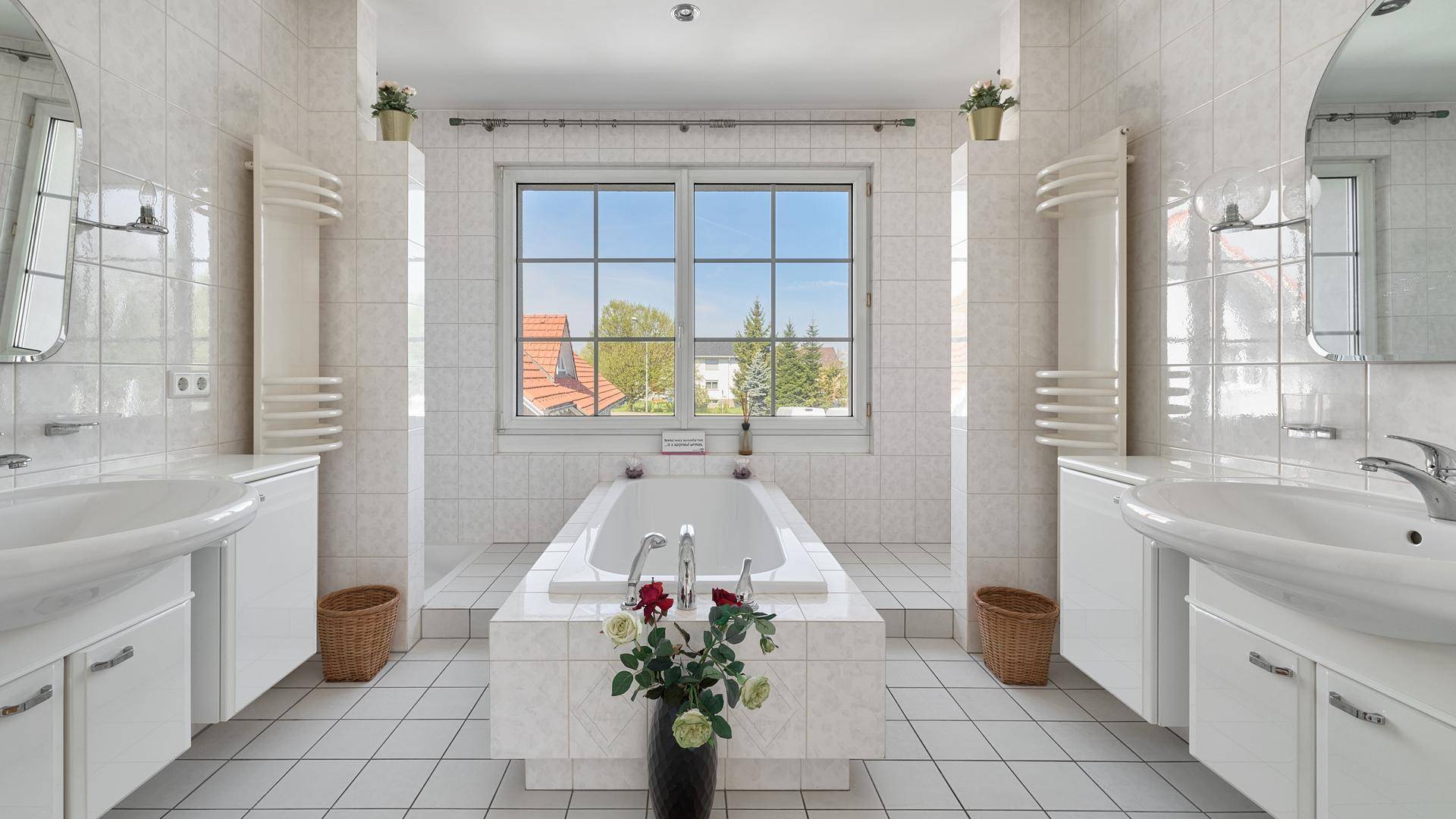 Geräumiges Badezimmer mit Badewanne, Doppelwaschbecken und Fenster.