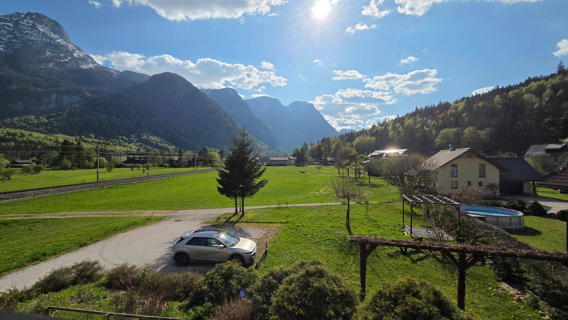 Malerische Landschaft mit Bergen, grünen Wiesen, einem Haus und einem Pool im Freien.