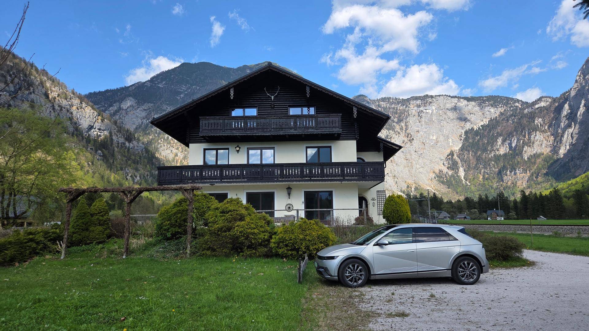 Charmantes Haus mit Balkonen und traditioneller Architektur vor einer beeindruckenden Bergkulisse.
