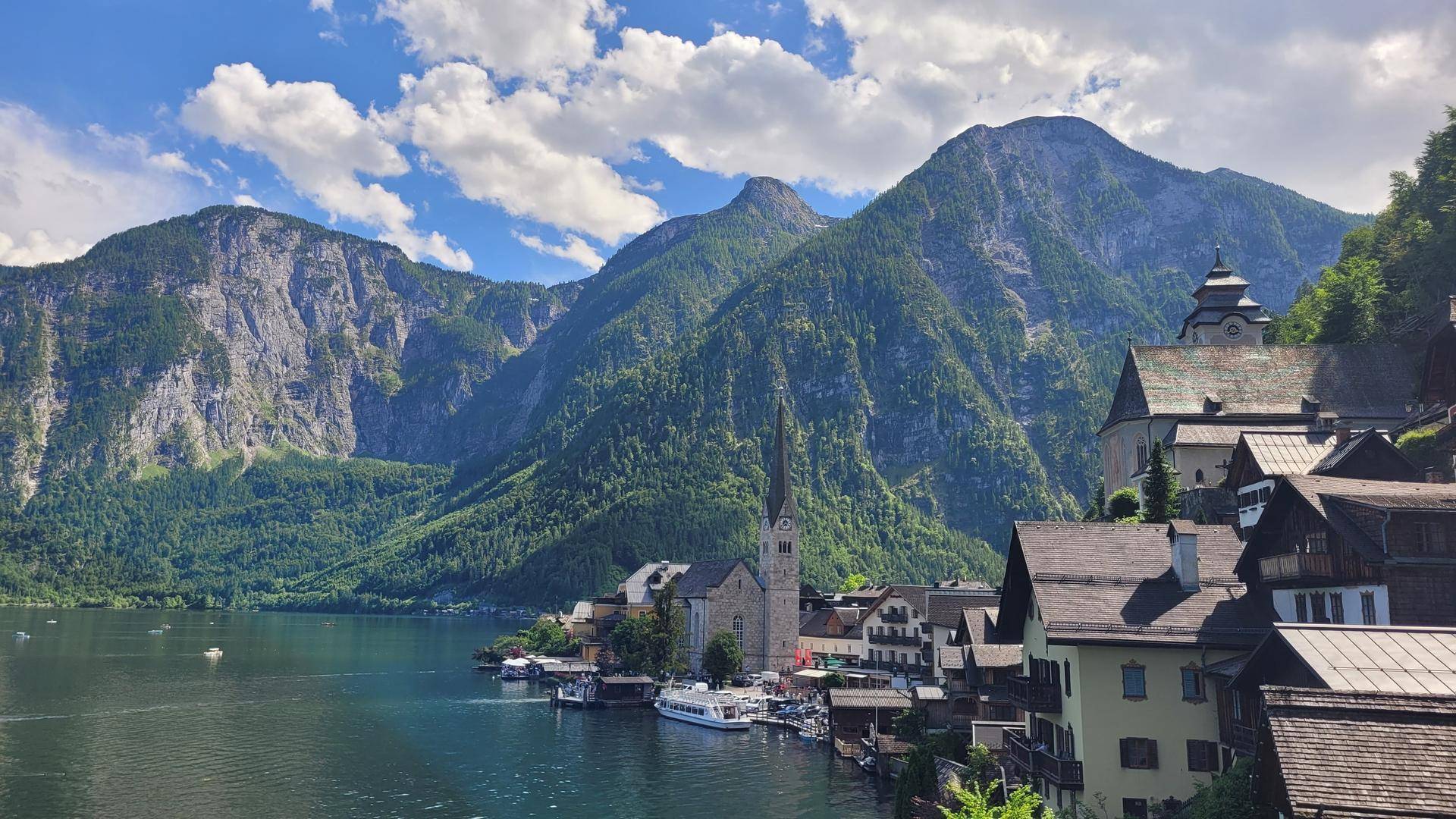 Malerische Ansicht einer Stadt am Seeufer, umgeben von hohen Bergen unter blauem Himmel.