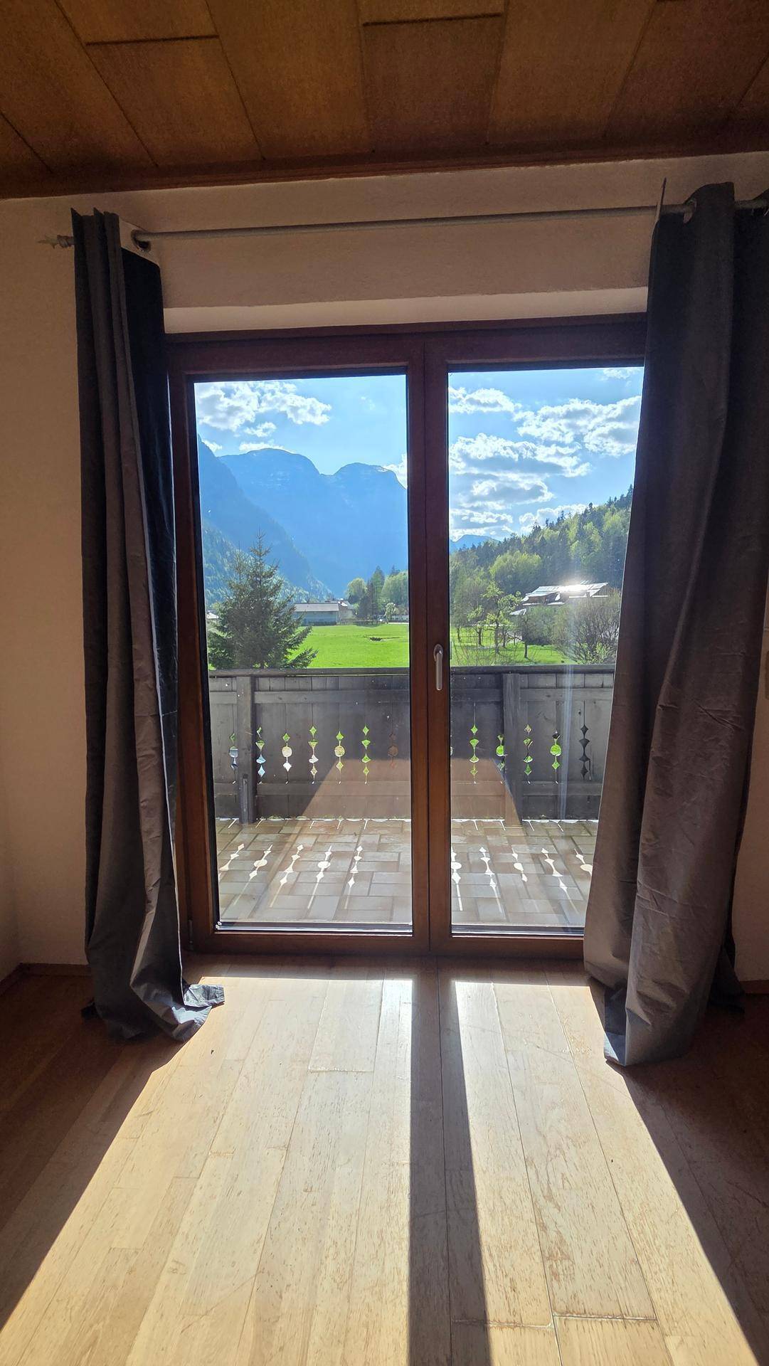 Heller Raum mit Holzboden und Zugang zu einem Balkon mit Bergblick.