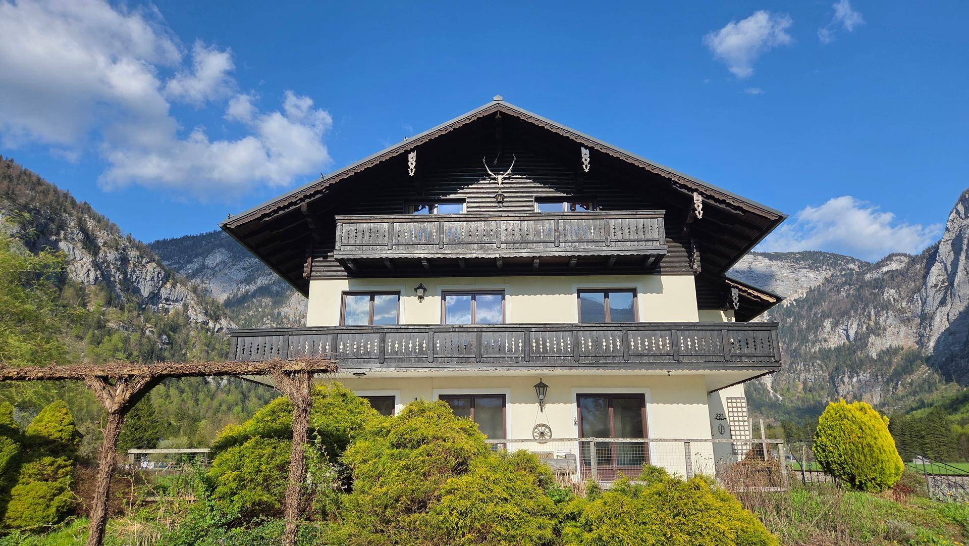 Traditionelles Haus mit mehreren Balkonen und Holzelementen, eingebettet in eine Berglandschaft.