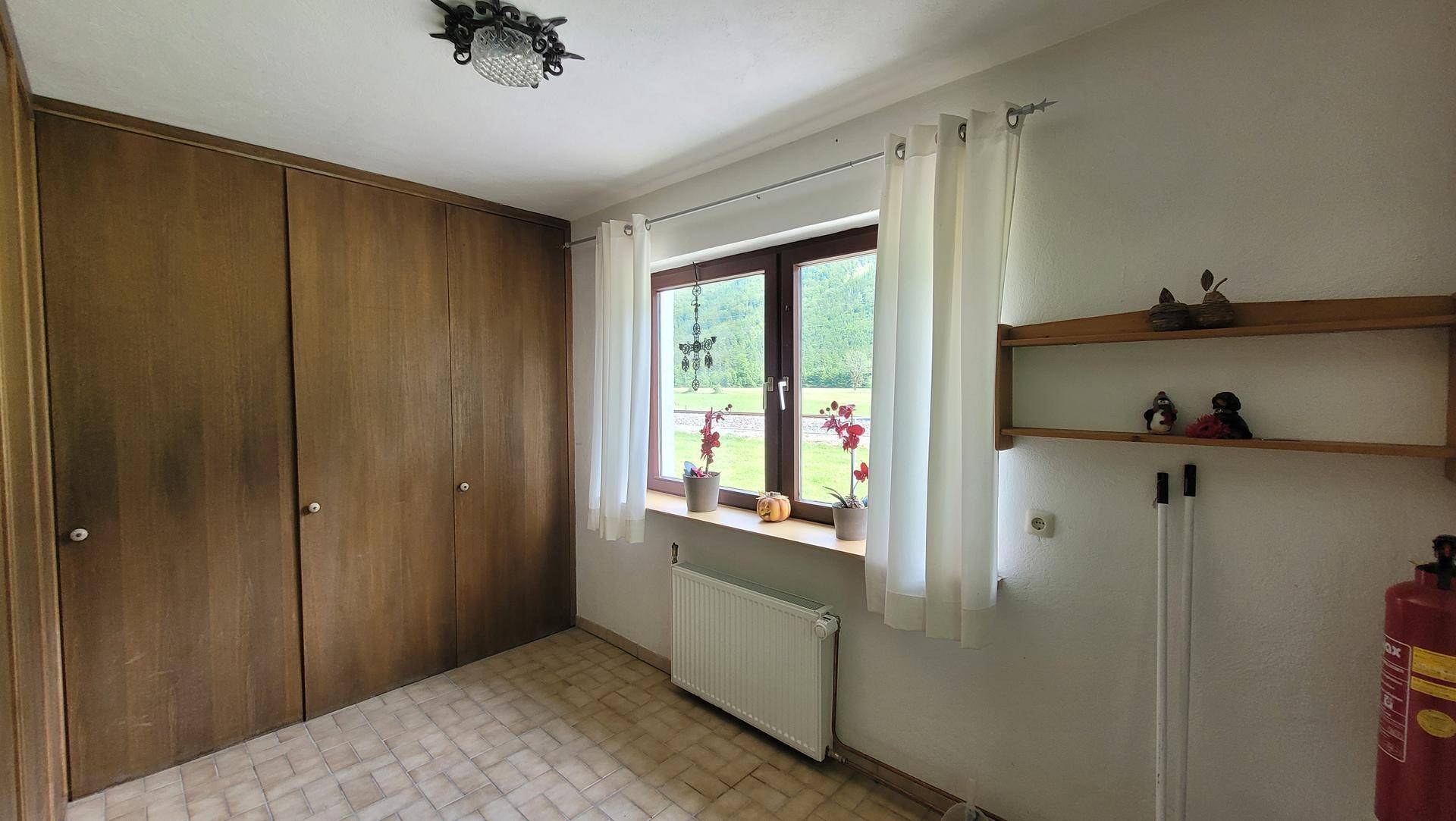 Praktischer Abstellraum mit integrierten Einbauschränken, Fenster und einem robusten Fliesenboden.