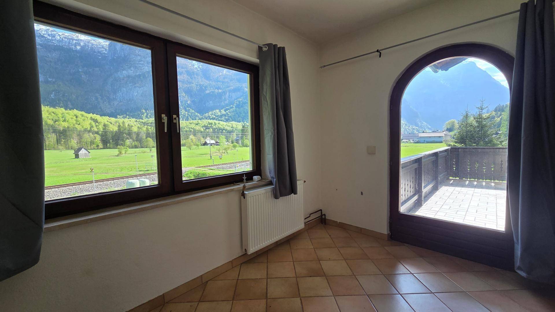 Heller Wohnraum mit Fliesenboden und direktem Zugang zu einem Balkon mit Bergblick.