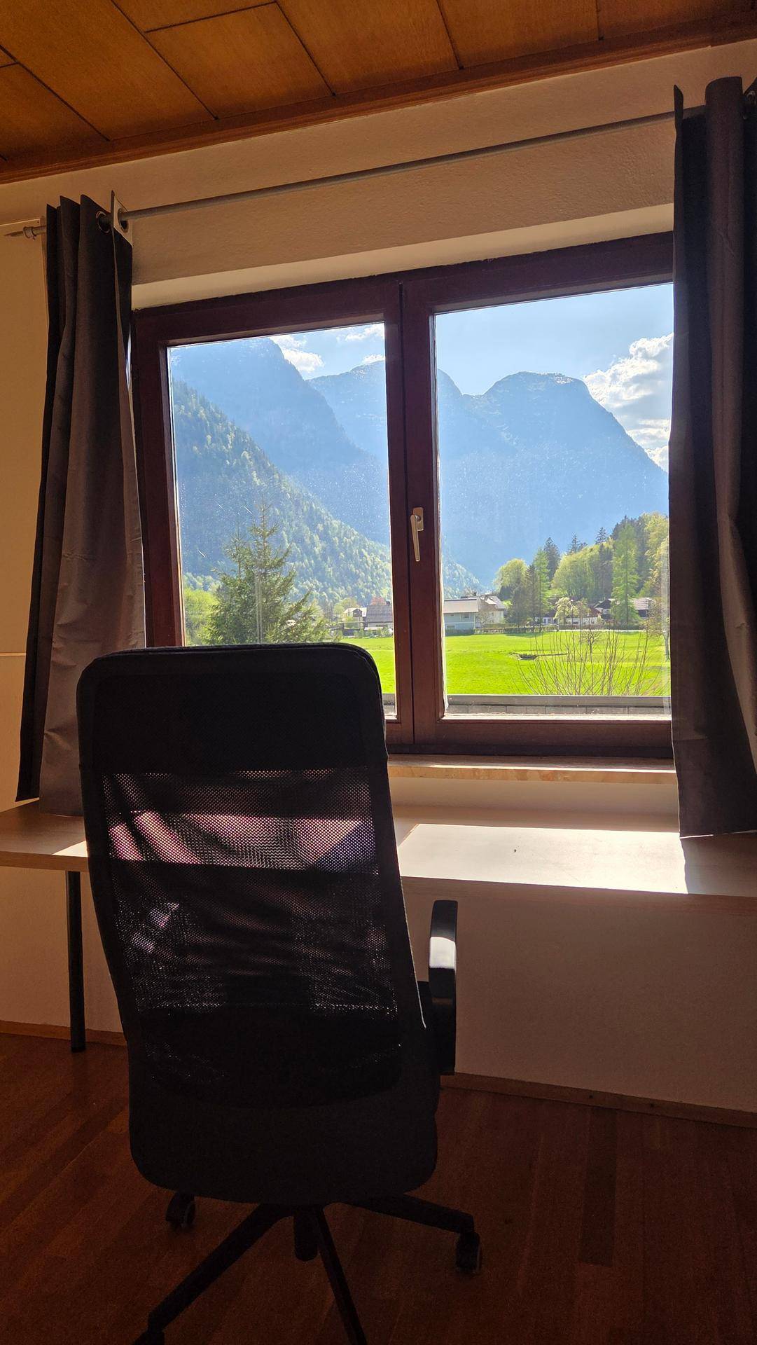 Blick aus einem Arbeitszimmer mit Schreibtisch auf eine beeindruckende Berglandschaft.