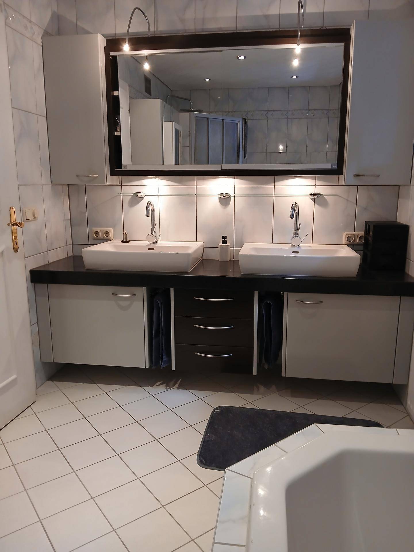 Geräumiges Badezimmer mit Doppelwaschbecken, großem Spiegel und Eckbadewanne.