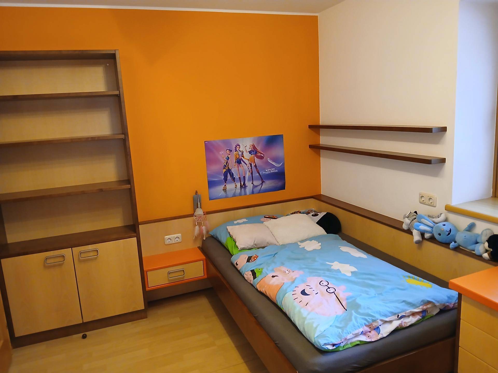 Kinderzimmer mit orangefarbener Akzentwand, Einzelbett und Holzregalen.