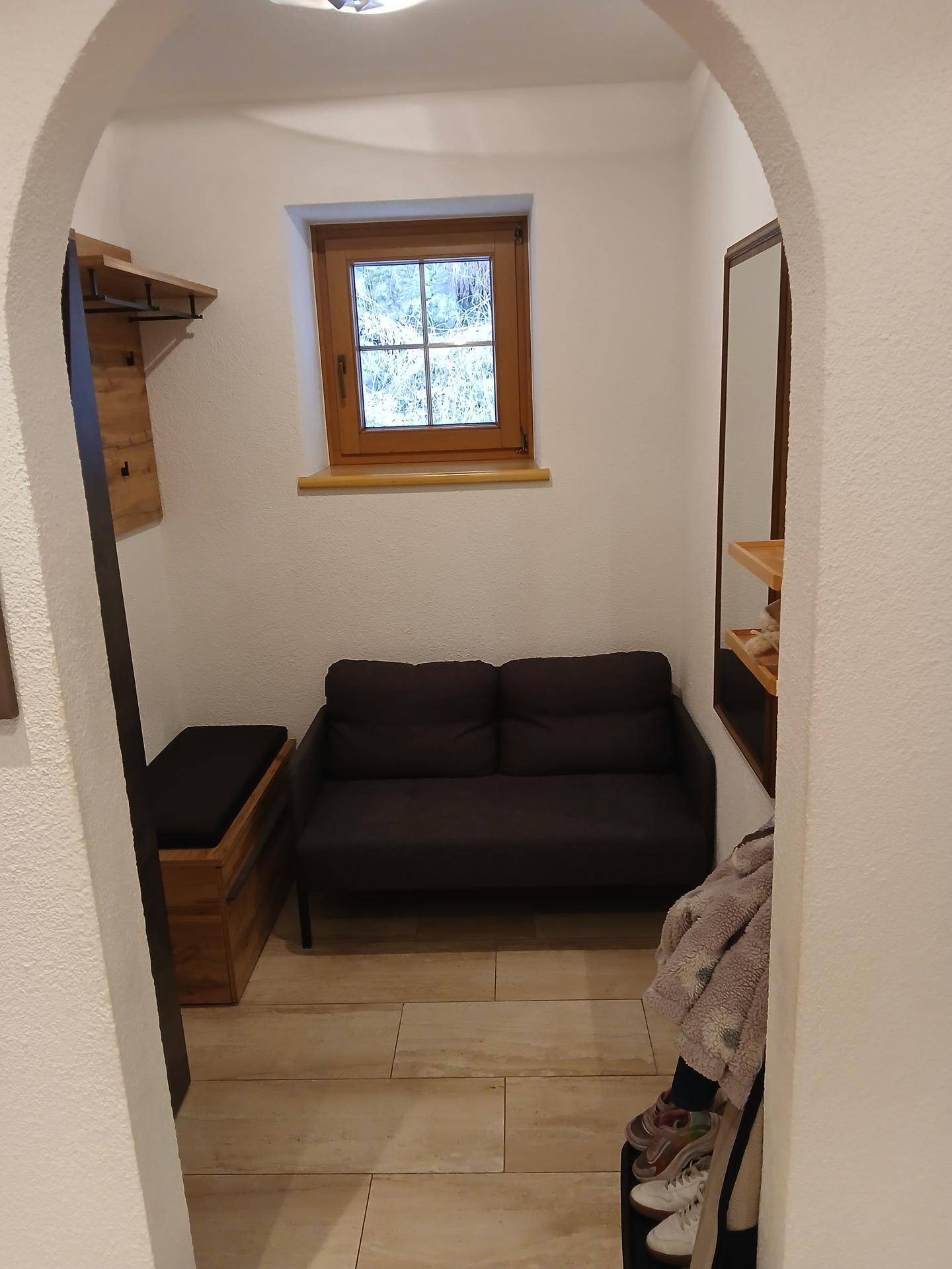 Gemütlicher Eingangsbereich mit Sitzgelegenheit, Garderobe und Fenster.
