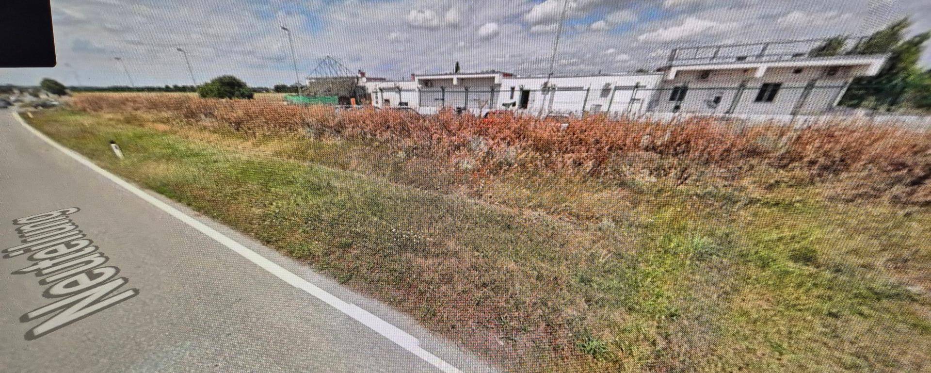 Weitläufige Ansicht des Gebäudes neben einer Landstraße mit trockener Vegetation und weitem Blick.