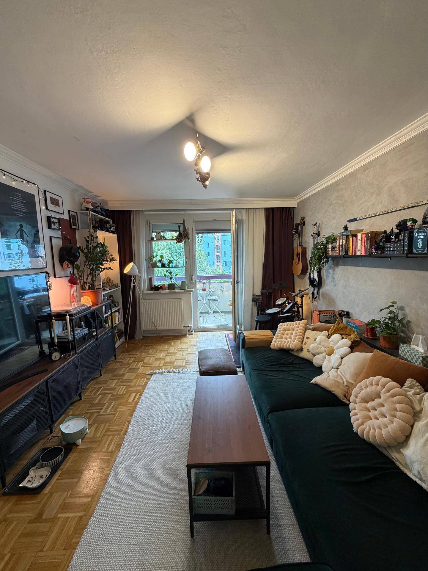 Helles Wohnzimmer mit Balkonzugang, Parkettboden und gemütlicher Einrichtung.