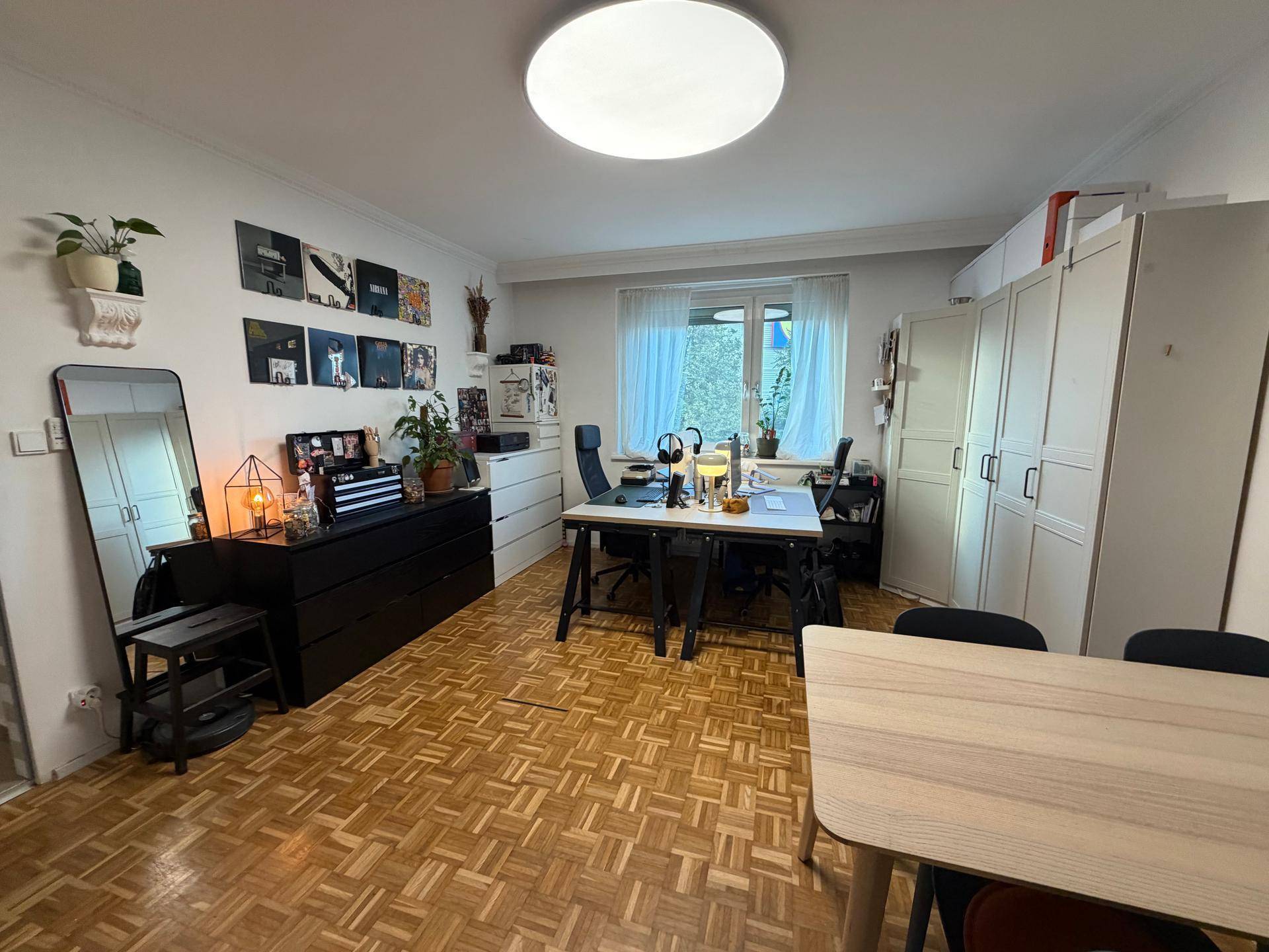 Helles Arbeitszimmer mit Parkettboden, großem Schreibtisch und viel Stauraum.