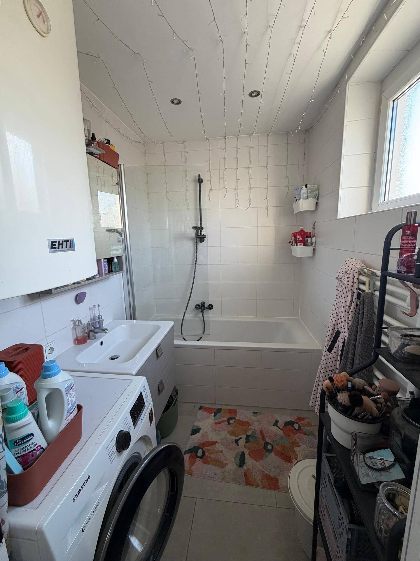 Helles Badezimmer mit Badewanne, Dusche, Waschbecken und Fenster.