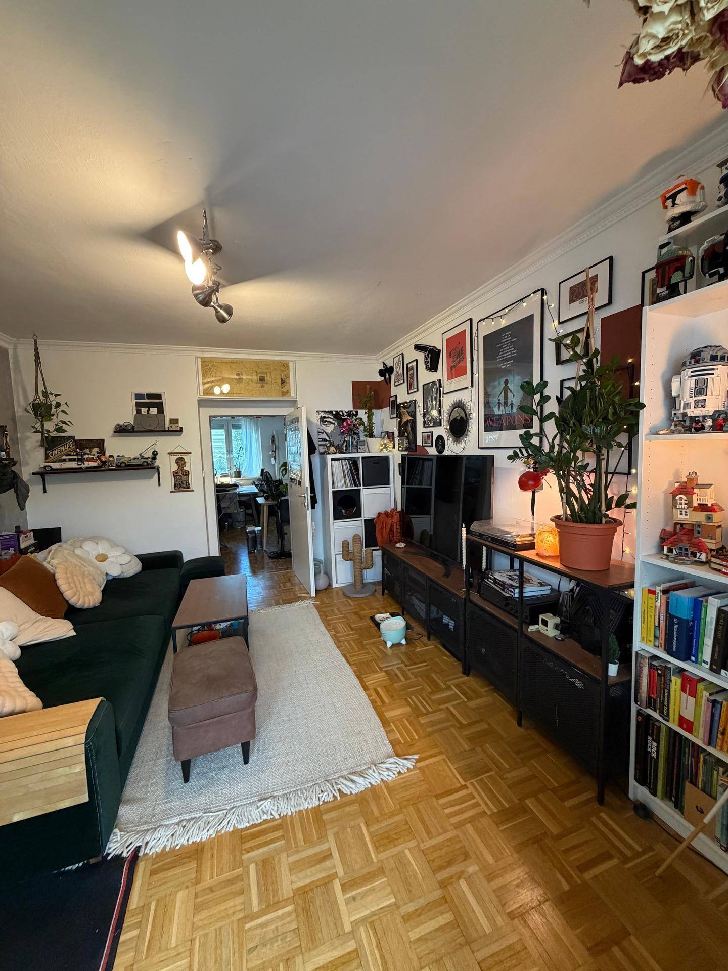 Geräumiges Wohnzimmer mit Parkettboden, dunklem Sofa und individueller Dekoration.