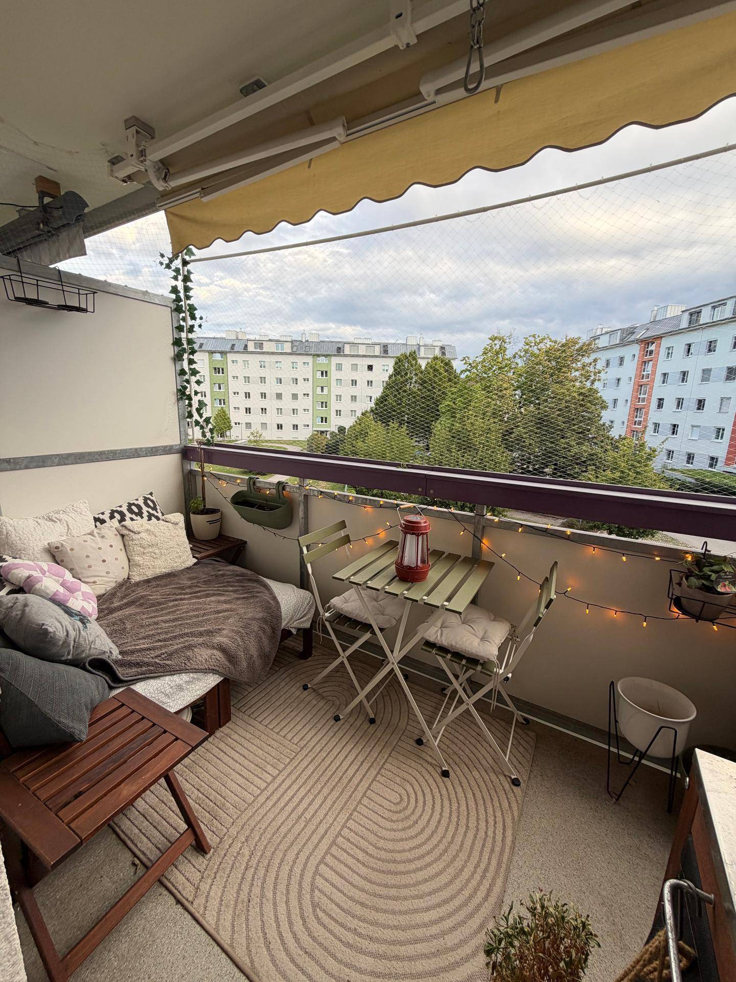 Möblierter Balkon mit Sitzgelegenheiten und Blick auf die umliegenden Wohngebäude.