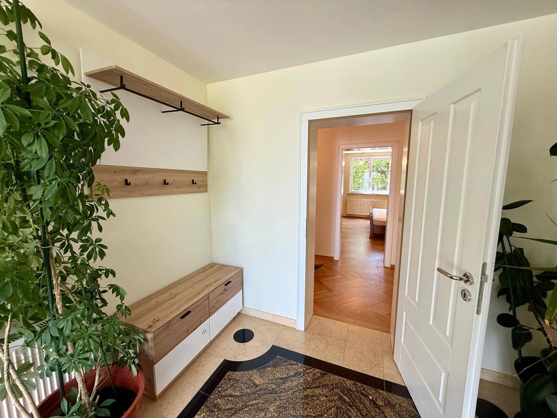 Heller Eingangsbereich mit Garderobe, Schuhschrank und Pflanzen, führt zu weiteren Räumen.