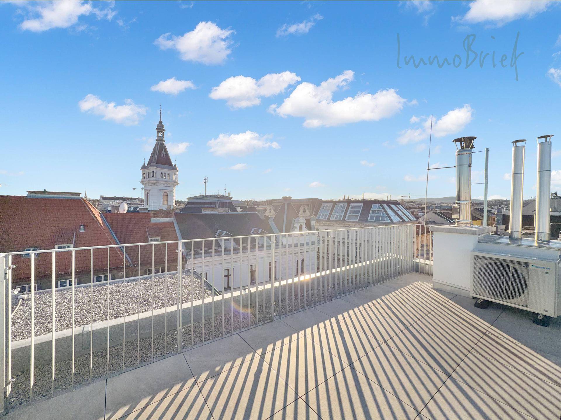 Weitläufige Dachterrasse mit Panoramablick über die Dächer der Stadt und historische Gebäude.