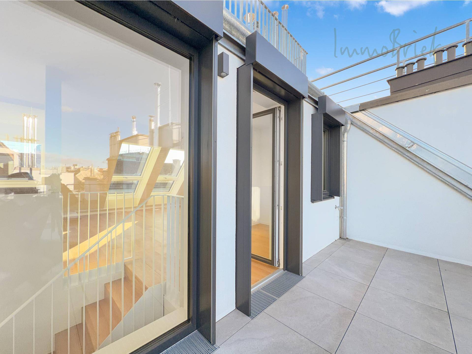 Zugang zur Dachterrasse mit modernen Fliesen und Blick auf die Stadtkulisse.