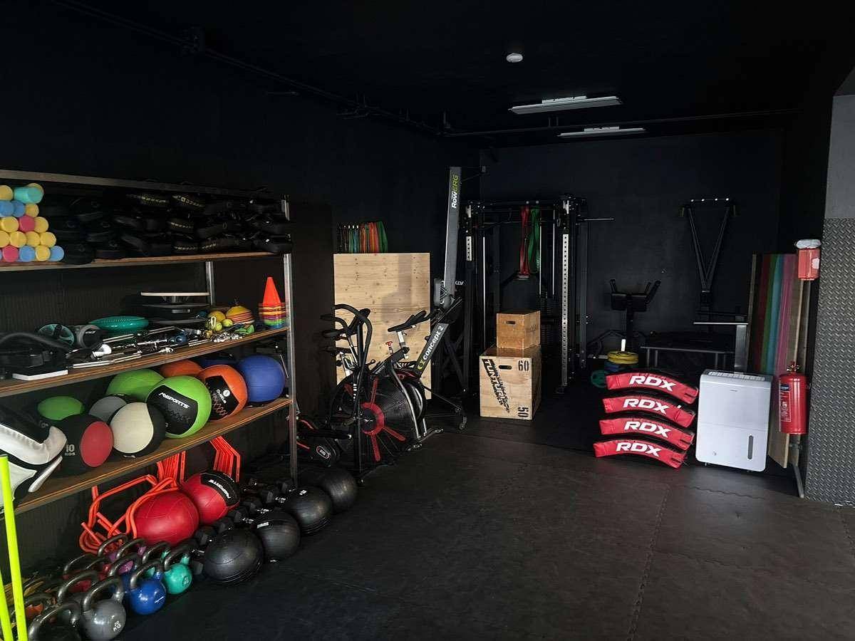 Gut ausgestatteter Fitnessraum mit verschiedenen Trainingsgeräten und Hanteln, bereit für intensives Training.