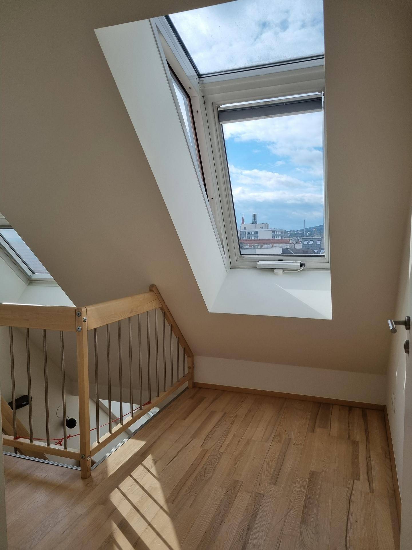 Flurbereich mit Holzboden und einem großen Dachfenster, das einen Blick auf die Stadt bietet.