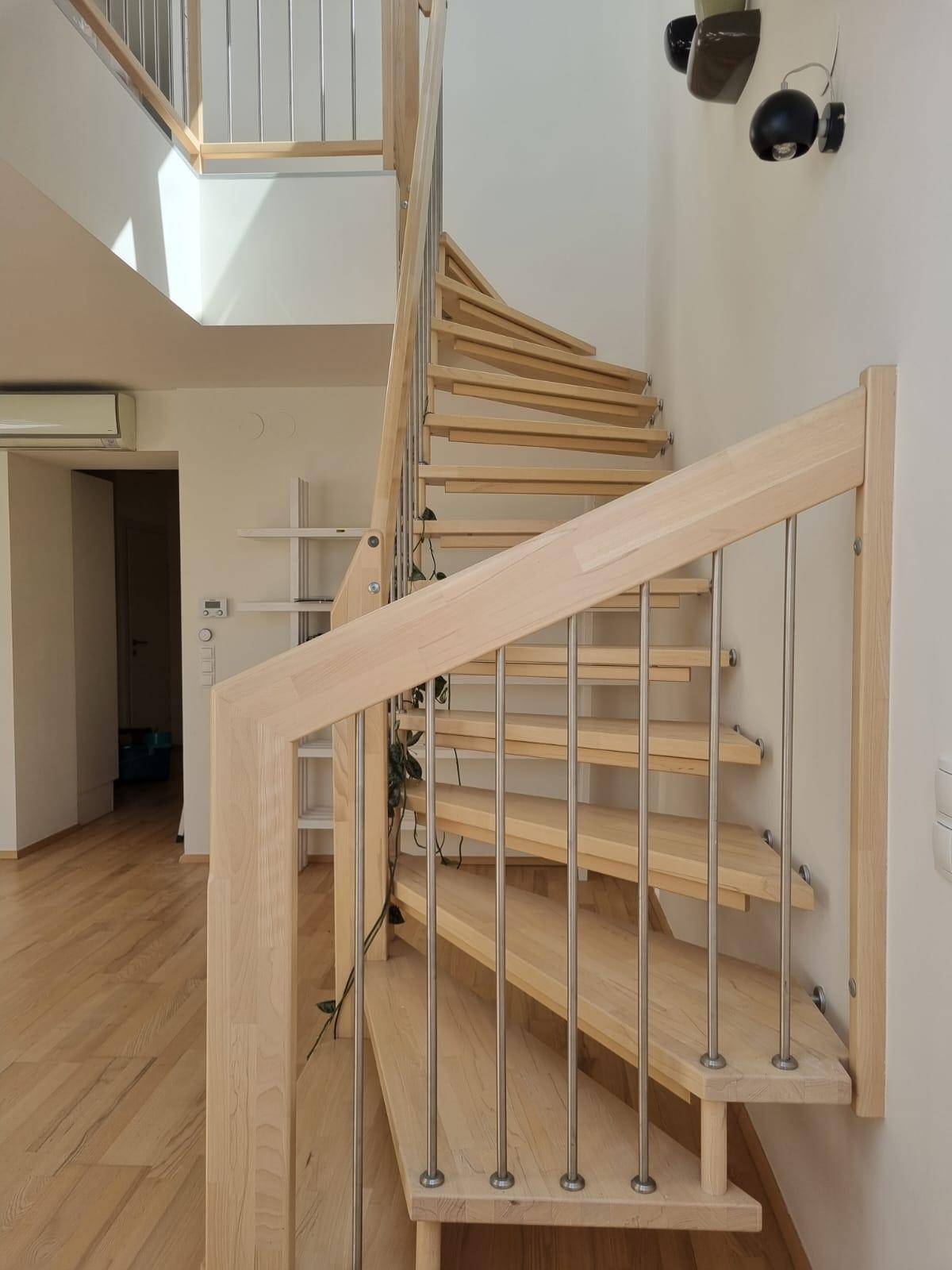Detailansicht der eleganten Holztreppe mit Metallgeländer, die die Ebenen verbindet.