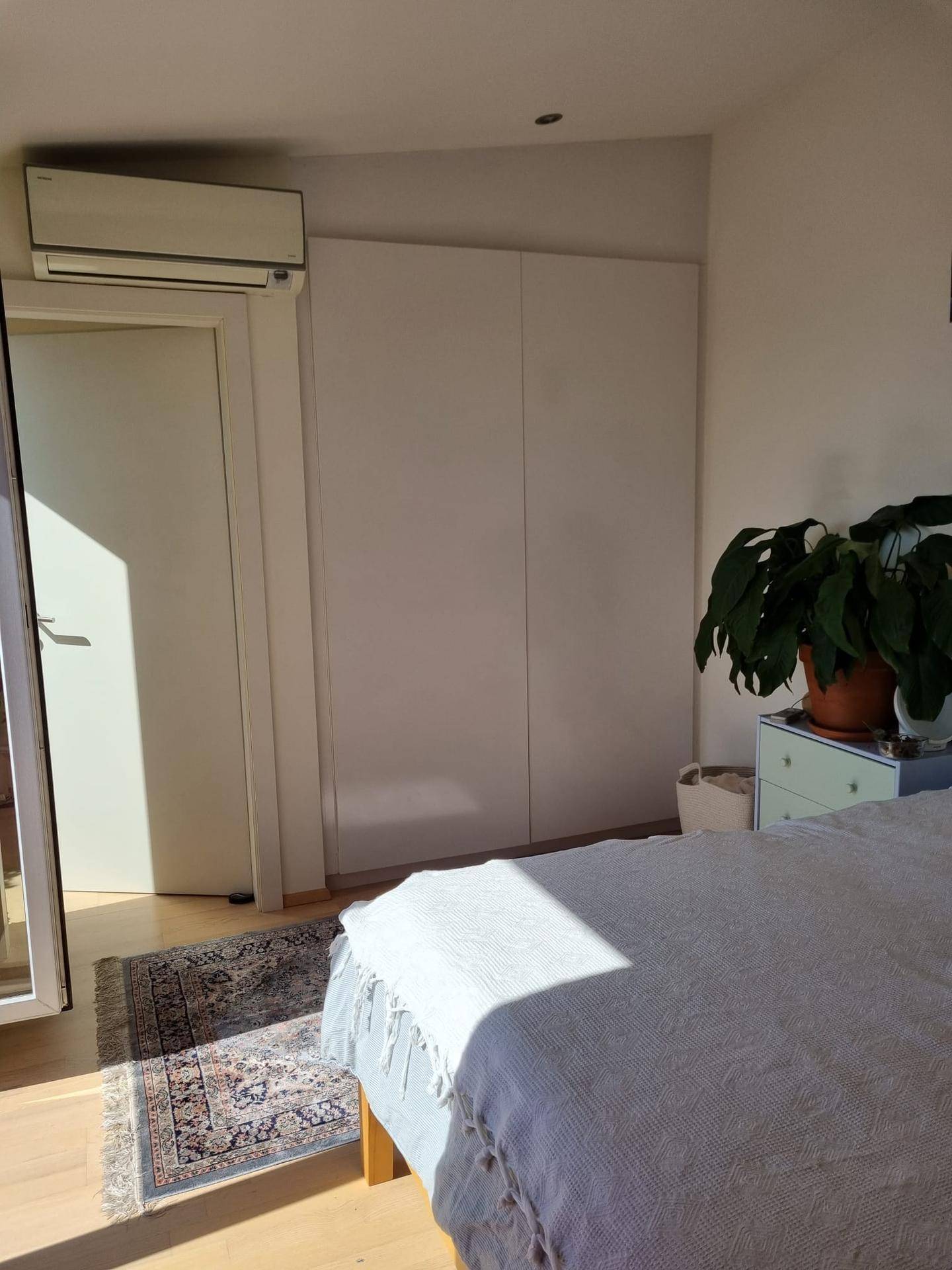 Schlafzimmer mit Einbauschränken und Klimaanlage, hell beleuchtet durch Sonnenlicht.