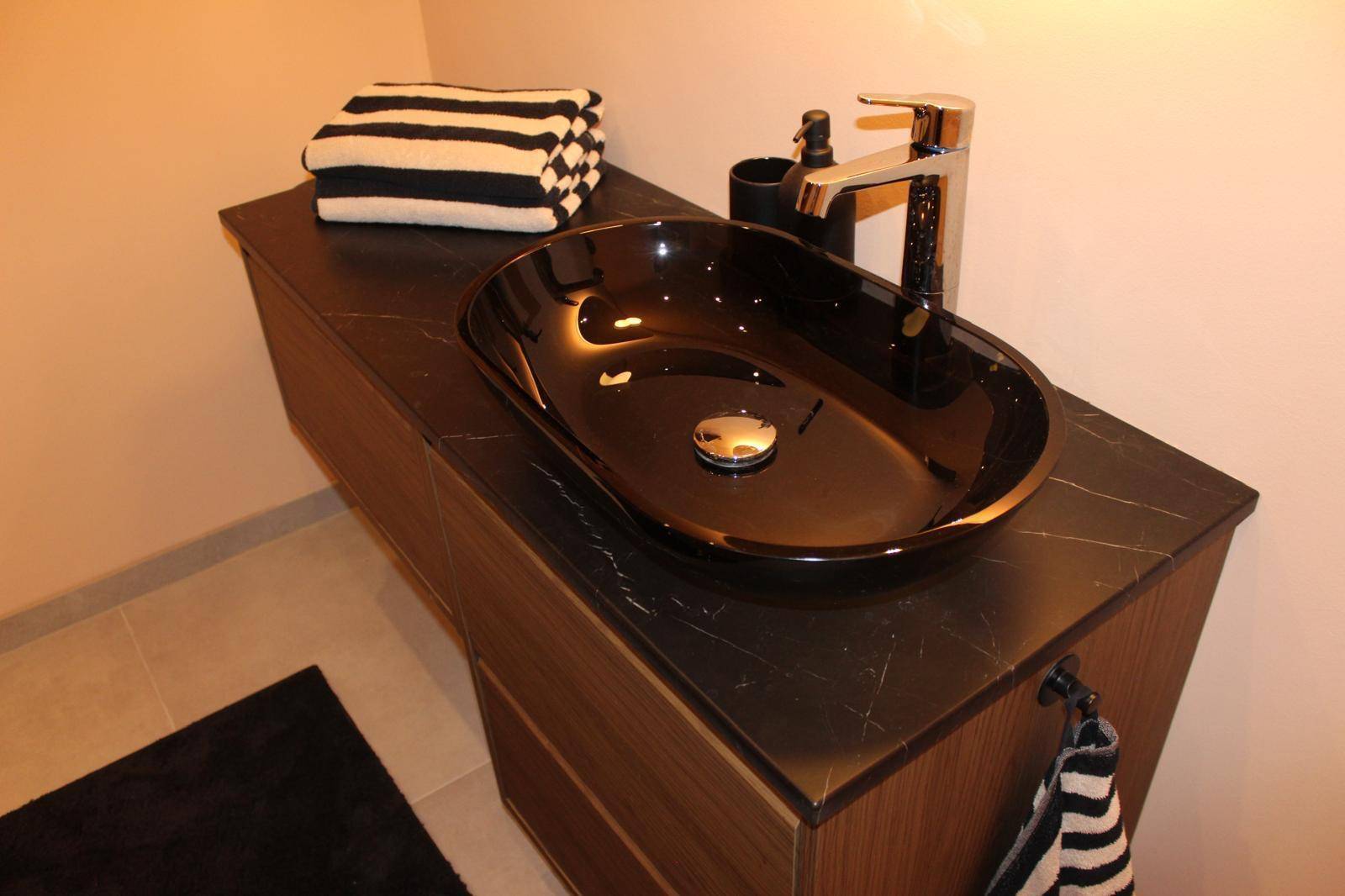 Modernes WC mit schwarzem Aufsatzwaschbecken und dunkler Waschtischplatte.