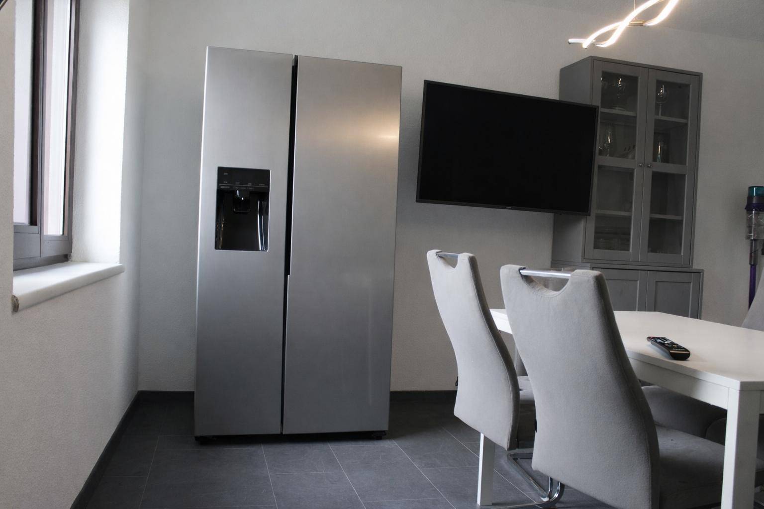 Essbereich mit großem Side-by-Side Kühlschrank, Esstisch und modernen Stühlen.