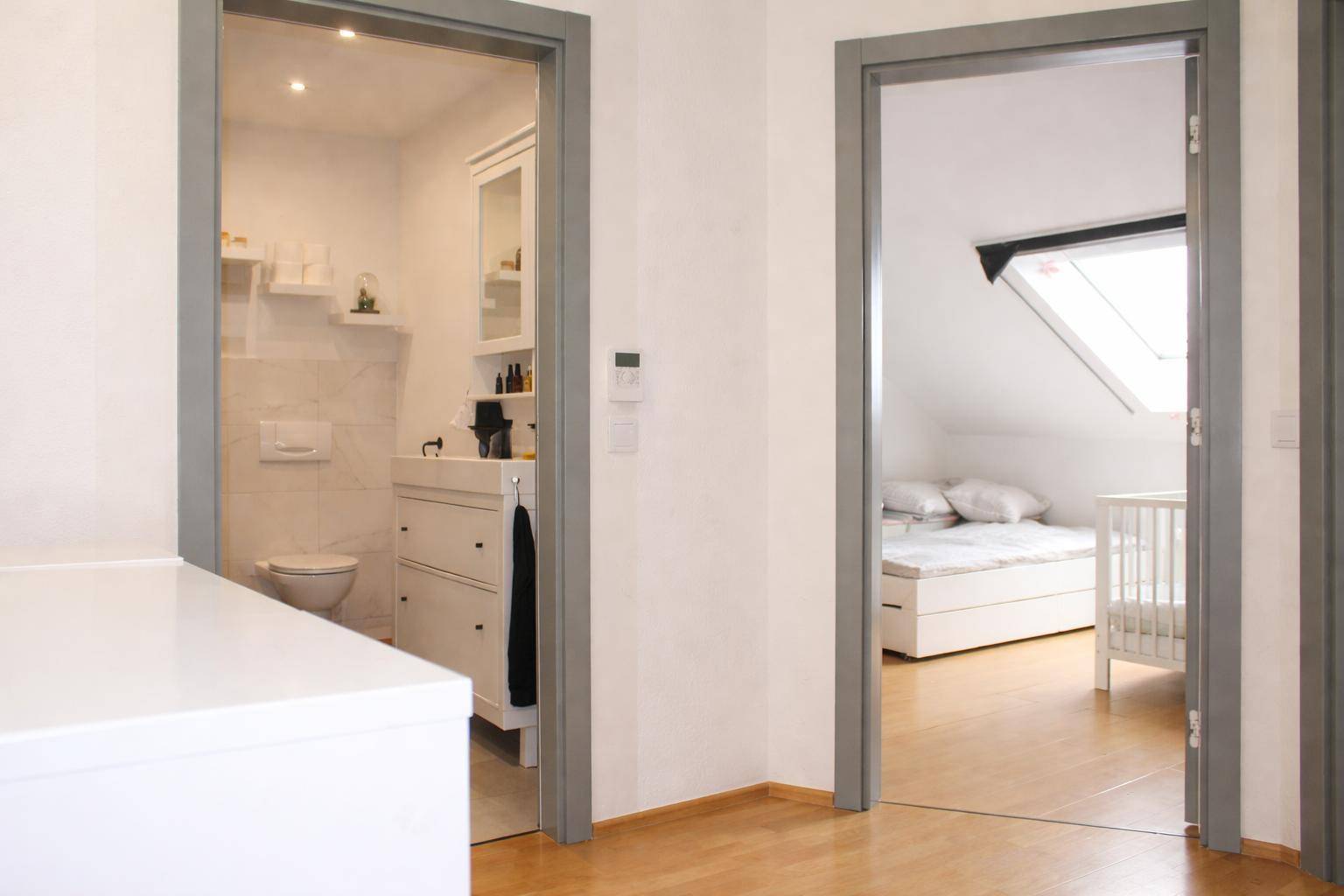 Flur mit Zugang zu einem modernen Badezimmer und einem hellen Schlafzimmer.