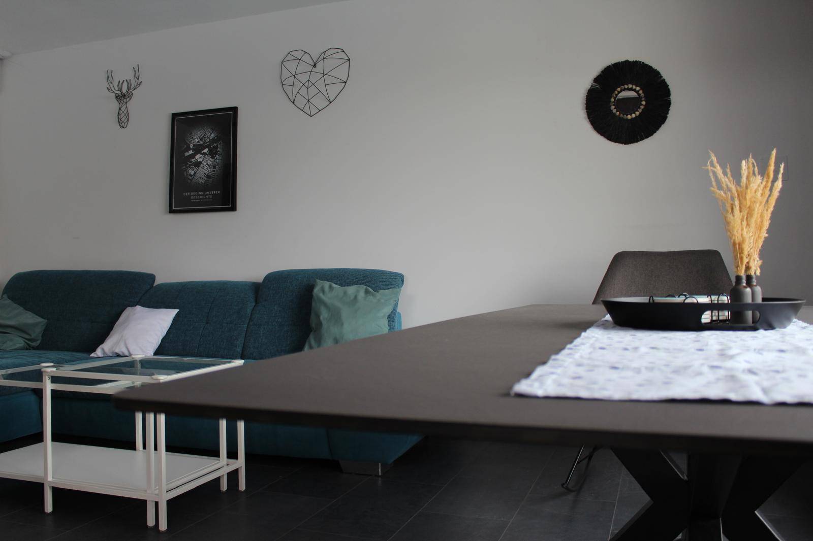 Gemütlicher Wohnbereich mit blauem Sofa, Couchtisch und modernem Esstisch.