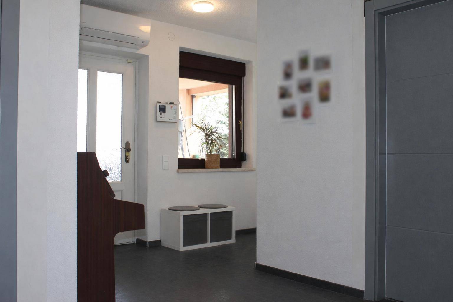 Eingangsbereich mit Fenster, kleiner Sitzbank und Zugang zu weiteren Räumen.