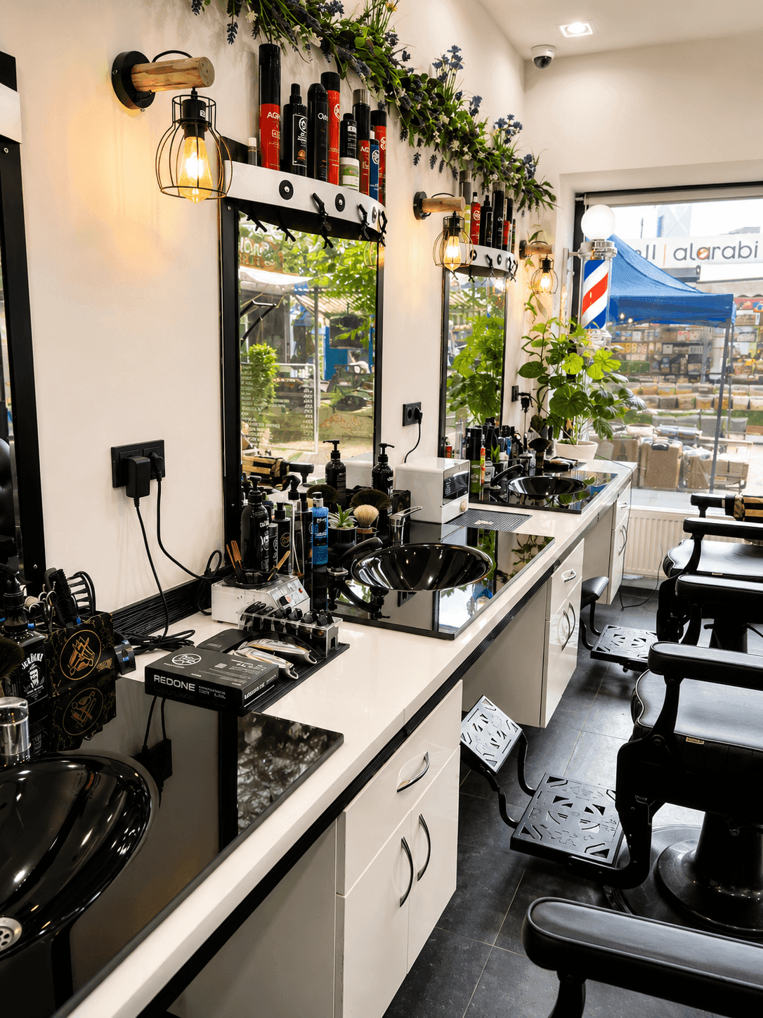 Reihe von Frisierplätzen mit schwarzen Waschbecken, Spiegeln und Produkten, beleuchtet durch moderne Lampen.
