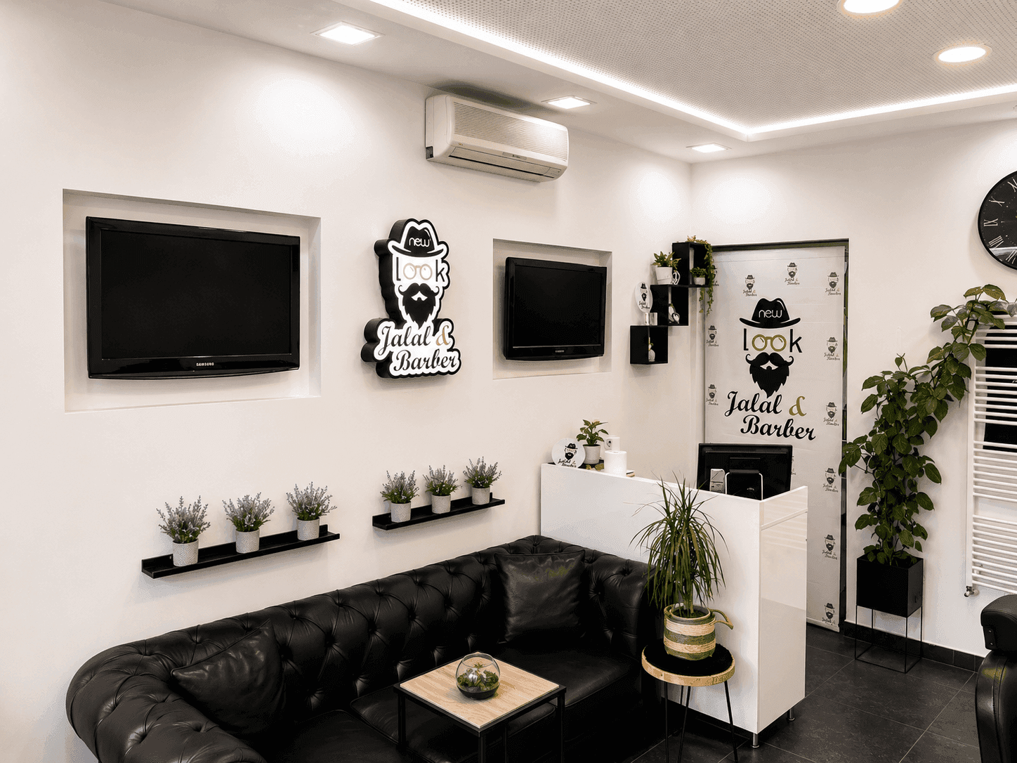 Empfangsbereich des Salons mit Ledersofa, Fernsehern und Klimaanlage an der Decke.