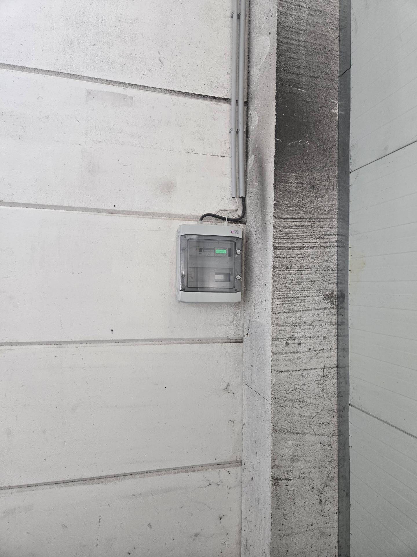 Nahaufnahme eines elektrischen Schaltkastens, der an einer Betonwand in der Industriehalle montiert ist.