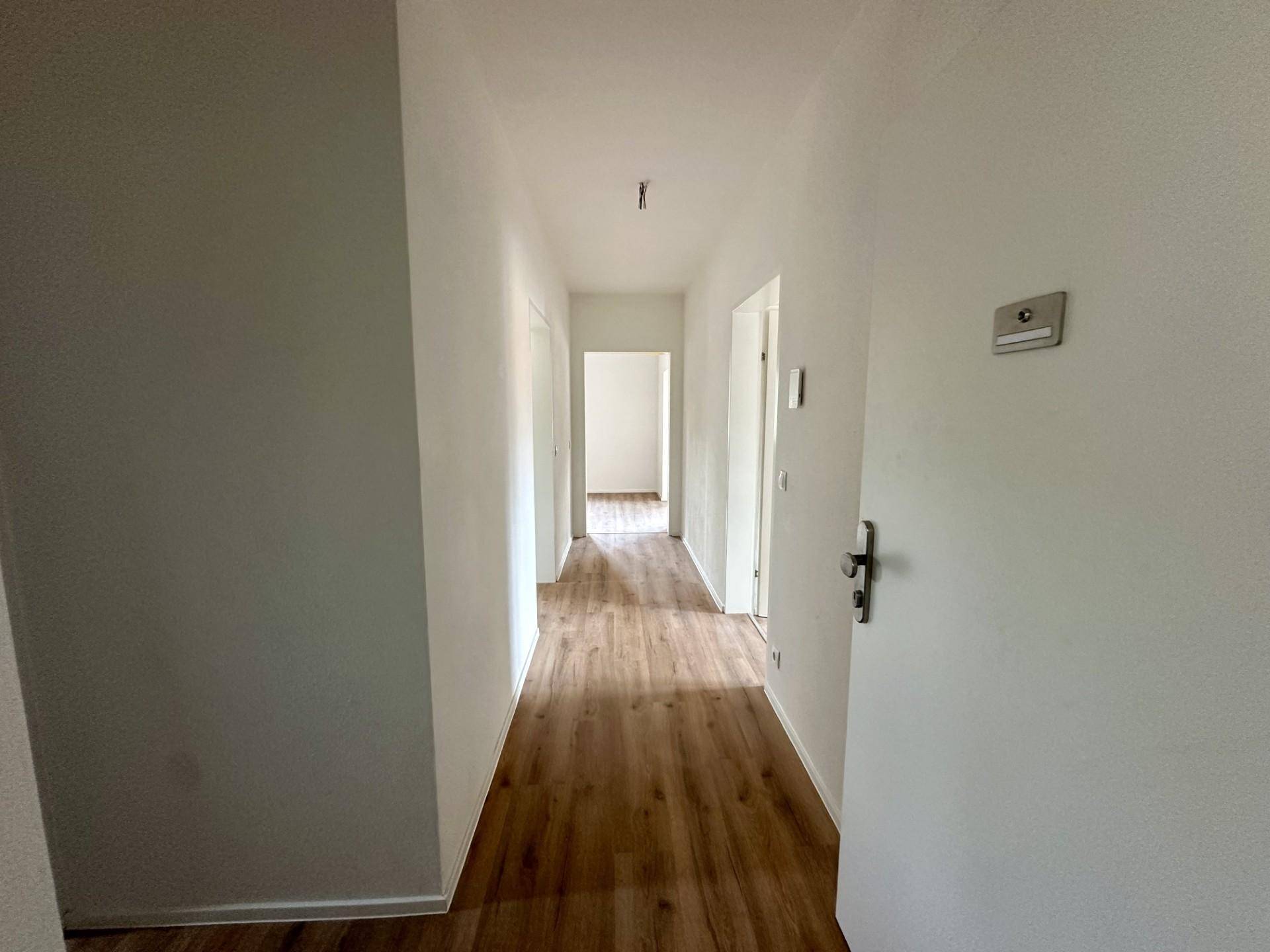 Heller Flur mit Laminatboden, der zu den verschiedenen Zimmern der Wohnung führt und gut gepflegt ist.