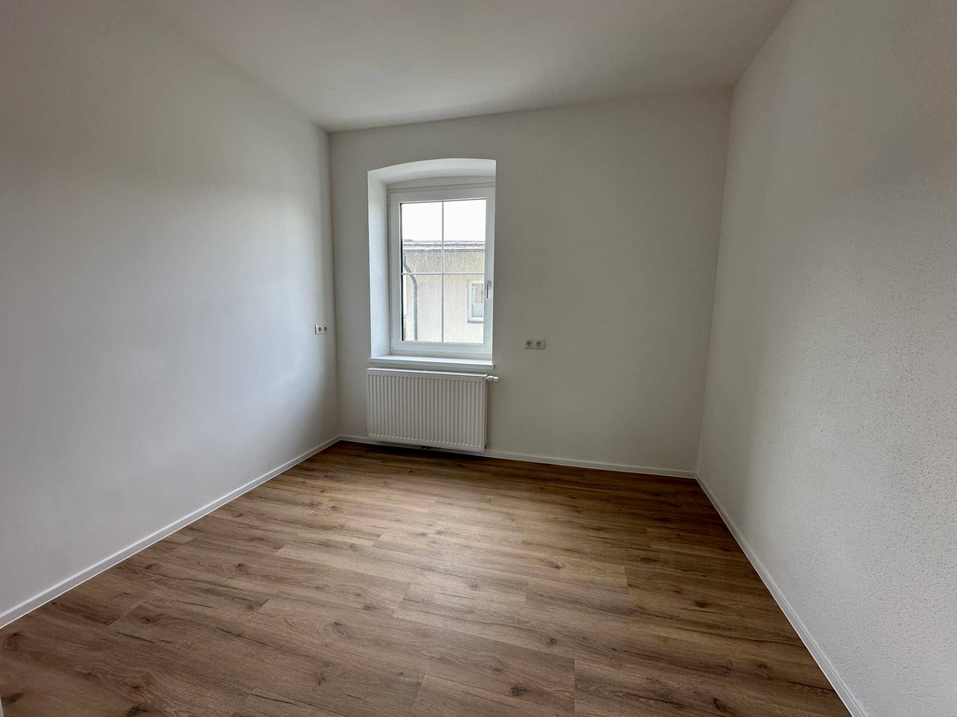 Ruhiges Zimmer mit Laminatboden und einem Fenster, ideal als Schlaf- oder Arbeitszimmer nutzbar.