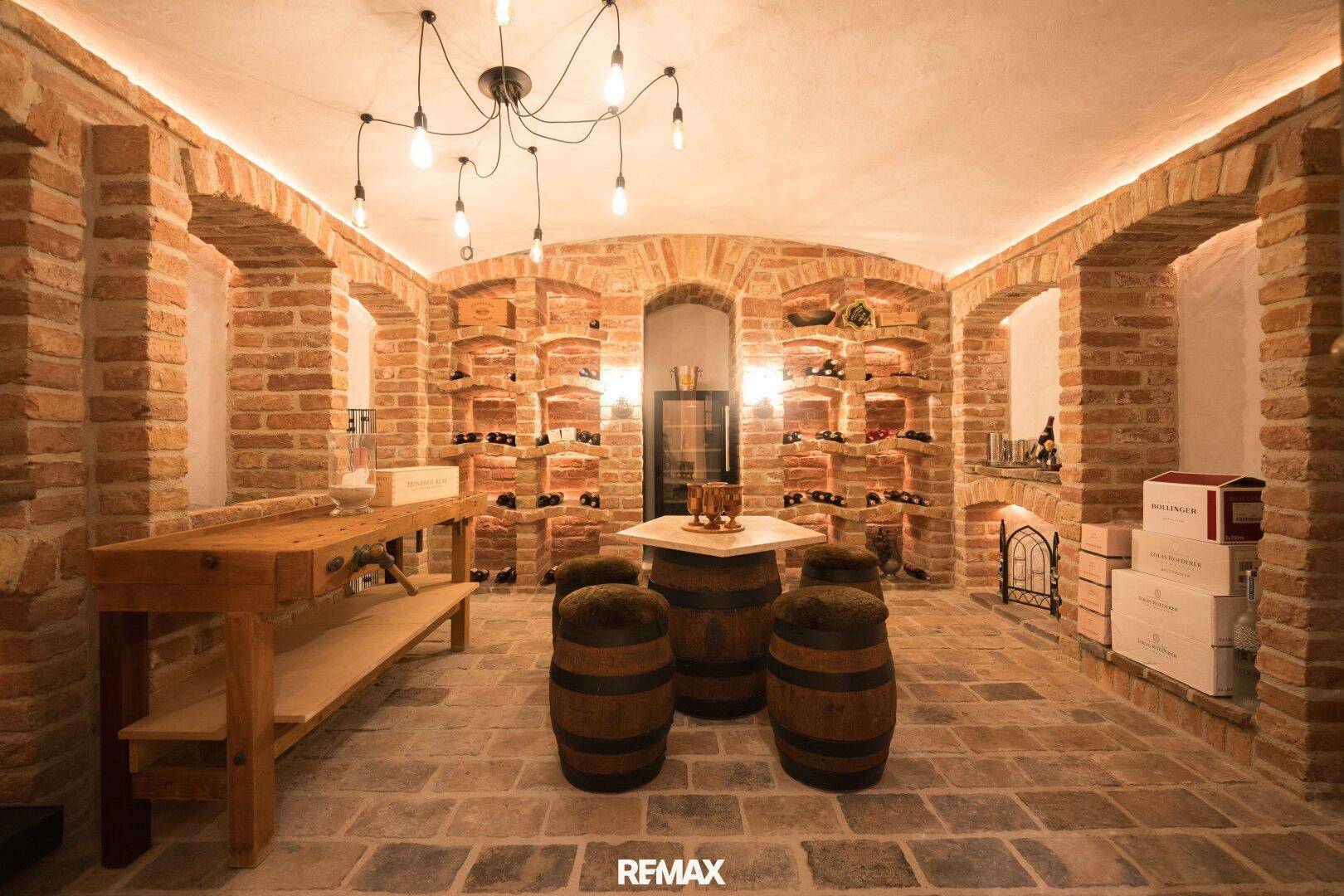 Rustikaler Weinkeller mit Ziegelgewölben, Weinregalen und gemütlicher Sitzecke.