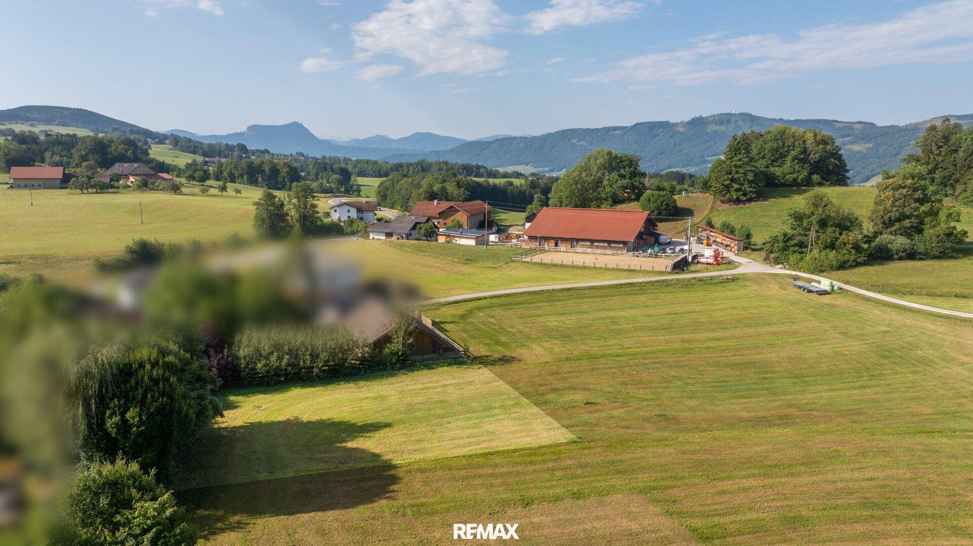 Weitläufiges Anwesen in ländlicher Idylle mit Reitplatz und Blick auf die umliegende Natur und ferne Berge.