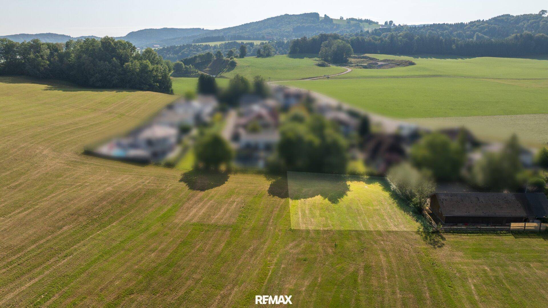 Luftaufnahme eines weitläufigen Feldes mit einem kleinen Gebäude und einem potenziellen Baugrundstück in ländlicher Lage.