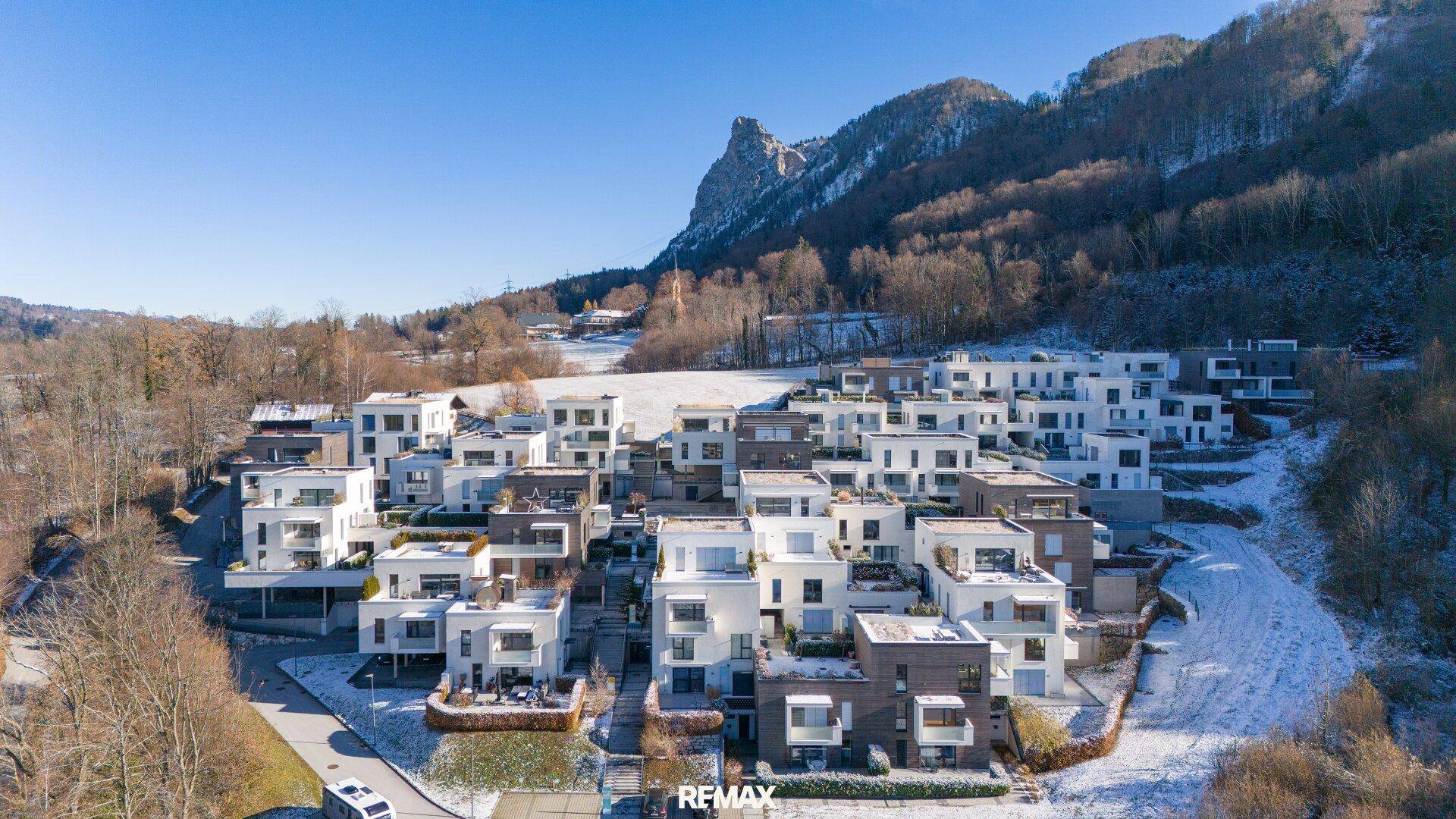 Weitläufige moderne Wohnanlage in einer verschneiten Hügellandschaft mit Blick auf ferne Berge.
