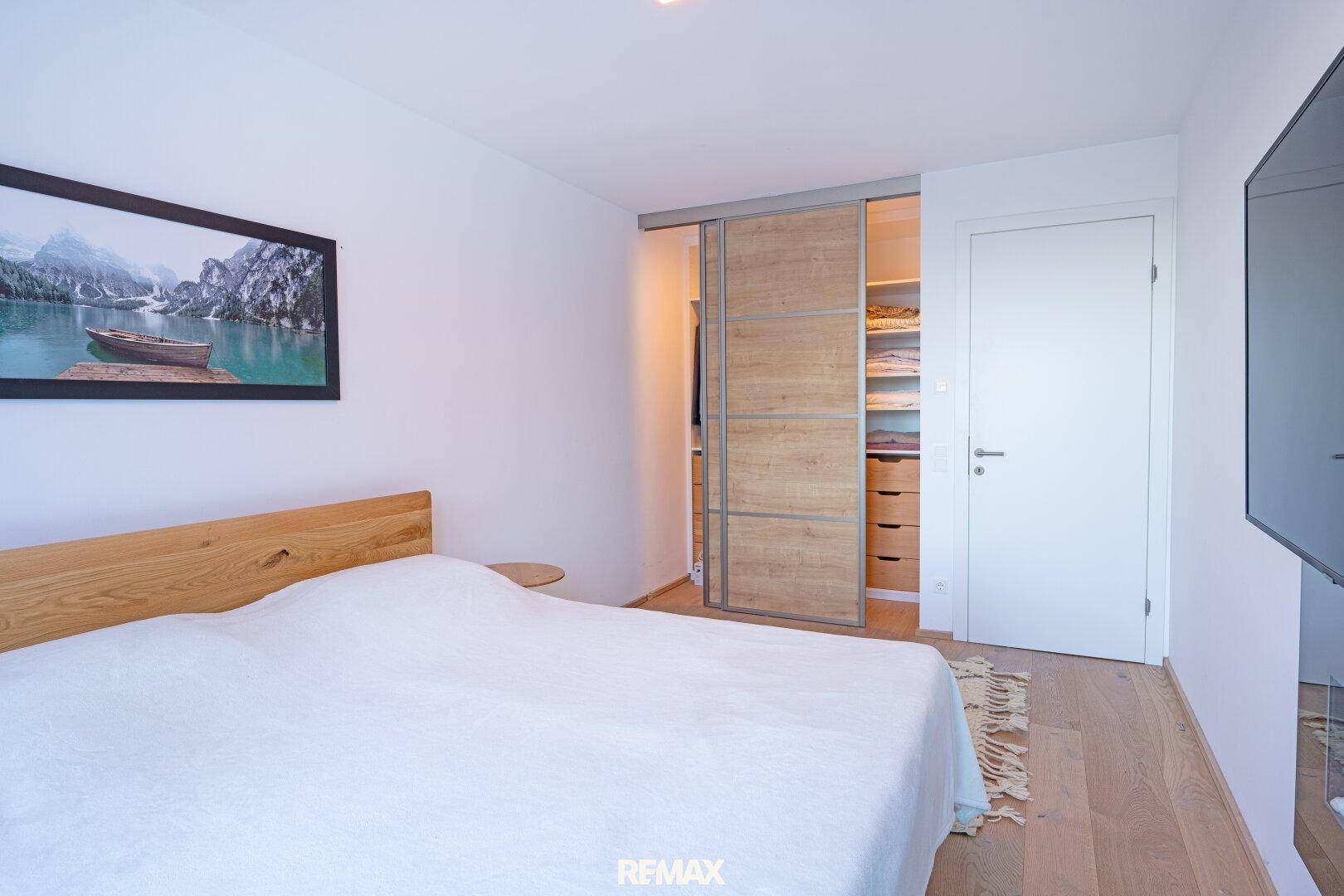 Schlafzimmer mit Holzboden, Doppelbett und integriertem Kleiderschrank mit Schiebetüren.